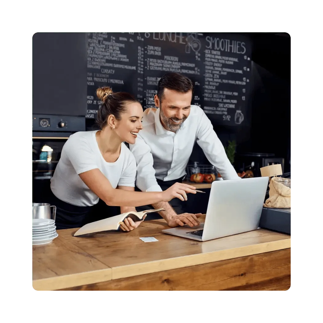 Restaurant team working together at a laptop on a wooden counter